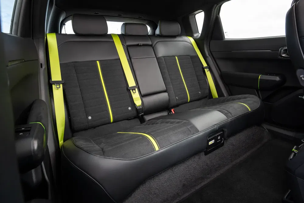 Intérieur de voiture moderne avec sièges arrière en cuir noir et bandes jaunes contrastantes.