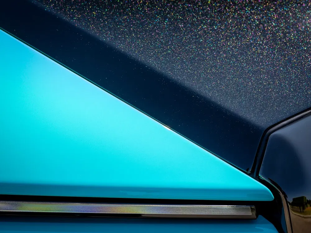 Design moderne d'une voiture électrique avec finition métallique scintillante et bleu turquoise distinctif.