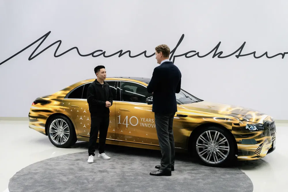 Mercedes-Benz S-Class dorée célébrant 140 ans d'innovation, avec deux hommes discutant devant.