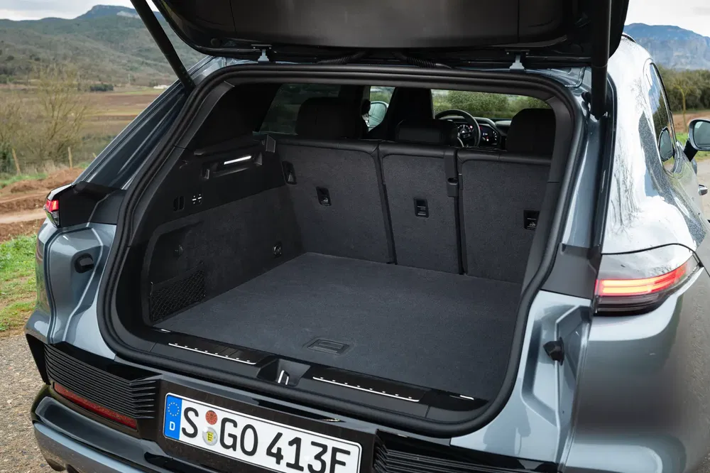 Coffre spacieux d'un SUV Porsche Cayenne, vue arrière ouverte sur paysage rural.