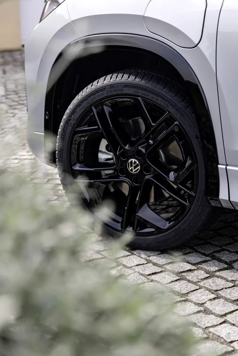 Glanzend zwarte Volkswagen-velg op geplaveide straat, modern en stijlvol ontwerp.