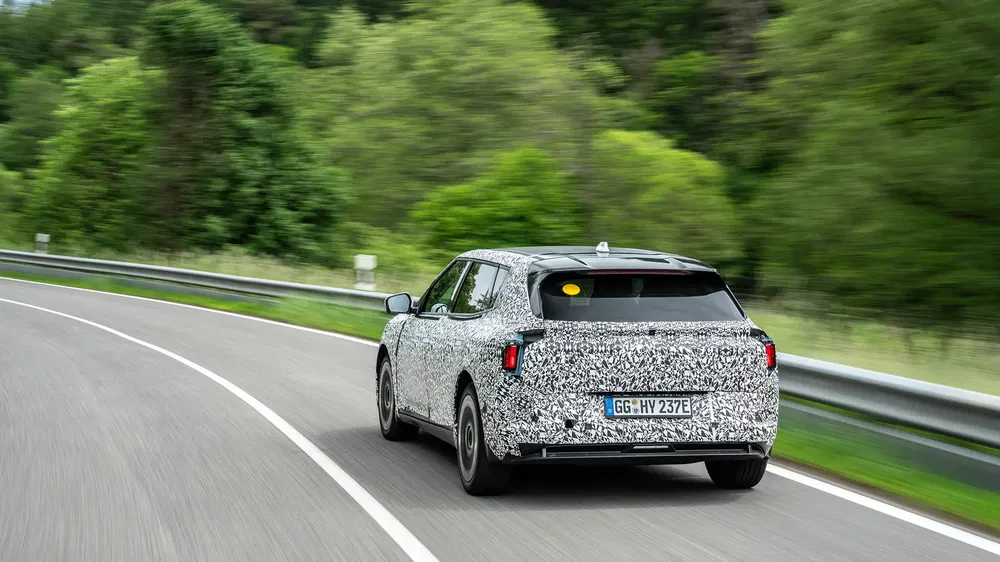 {"fr":"Prototype de voiture électrique camouflée sur route sinueuse entourée de verdure dense.","nl":"Camouflage elektrische auto op bochtige weg, omringd door weelderige natuur."}
