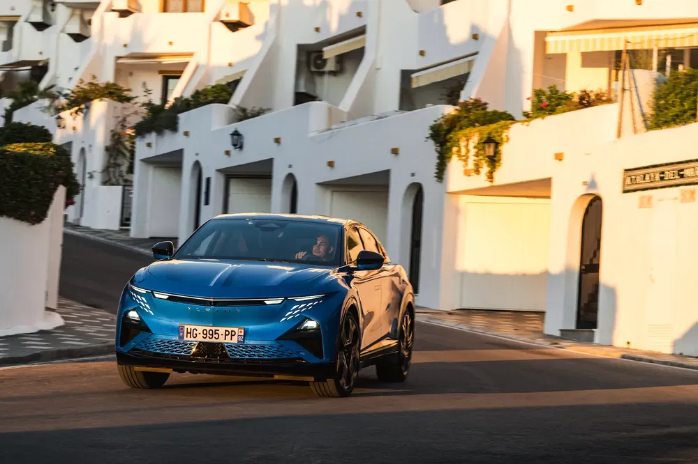 Blauwe Peugeot 408 op een woonstraat met witte huizen.