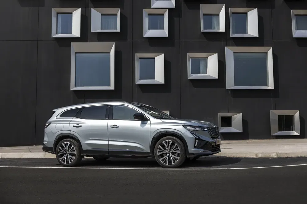 Moderne zilveren SUV voor zwart gebouw met geometrische ramen.