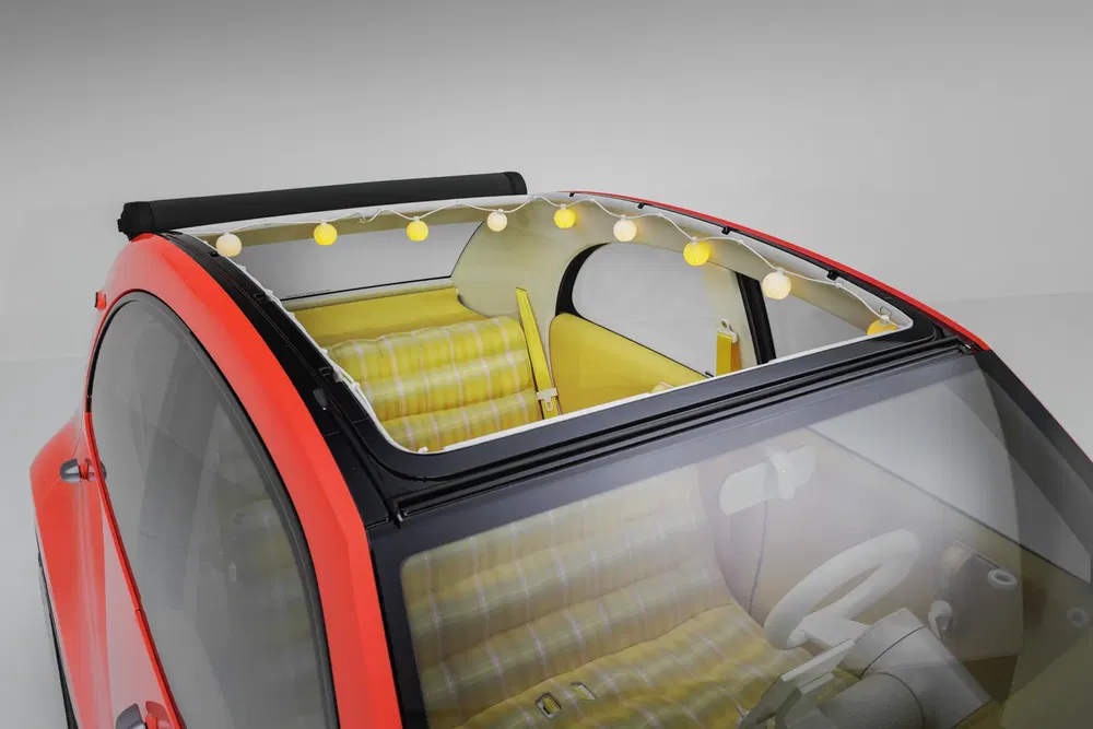 Toit de Citroën 2CV rouge avec intérieur jaune et guirlande lumineuse décorative.