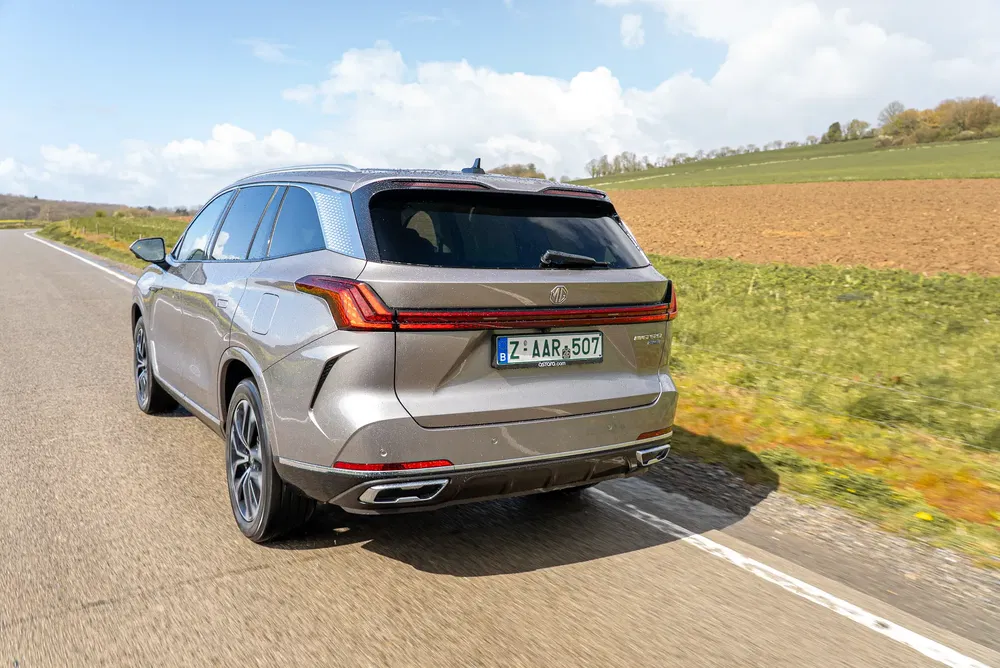 Zilveren MG SUV rijdt op een zonnige plattelandsweg.