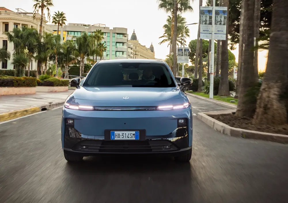 Voiture électrique HiPhi X sur route urbaine bordée de palmiers.