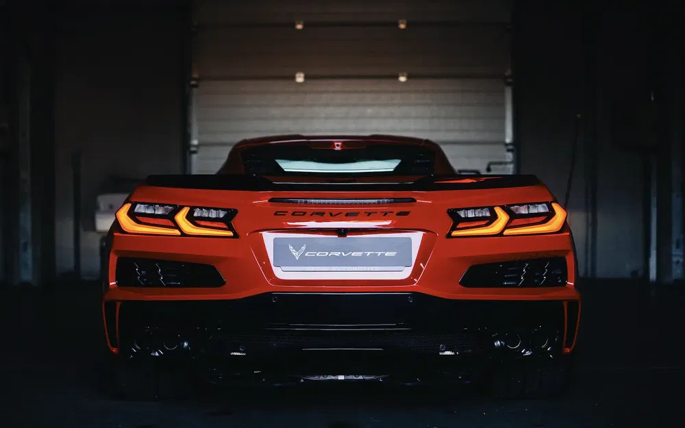 Achteraanzicht van een felrode Corvette in een donkere garage.