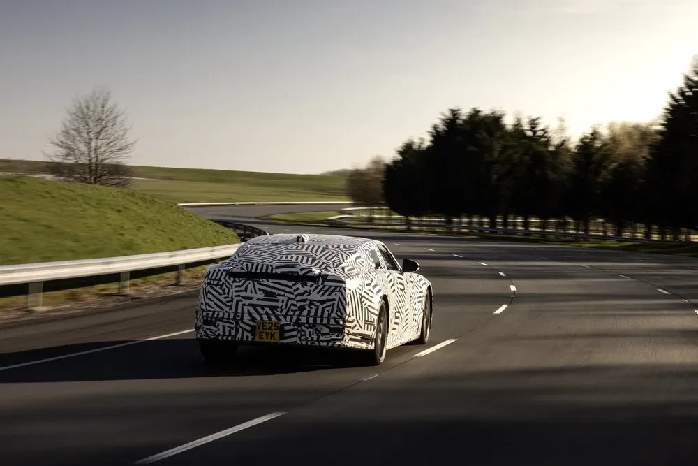 Gecamoufleerde auto op een bochtige weg, mogelijk bezig met het testen van nieuwe functies.