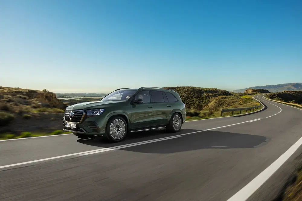 Mercedes GLS vert roulant sur autoroute sinueuse par temps ensoleillé.