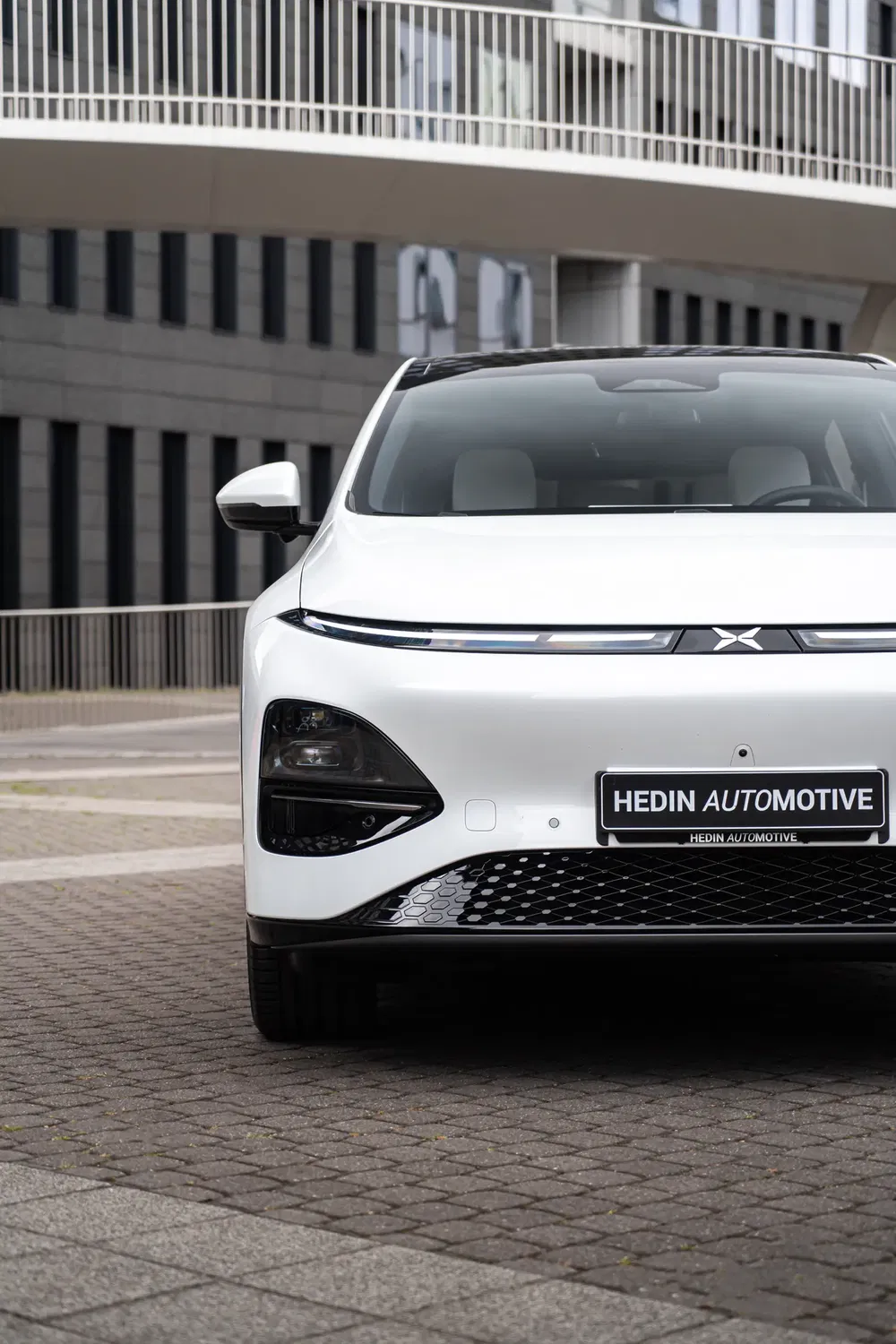 Voiture électrique élégante XPeng P7 blanche devant un immeuble moderne.