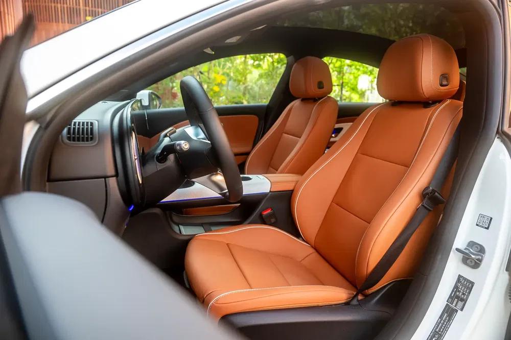 Interieur van een auto met elegante bruine leren stoelen en modern ontwerp.