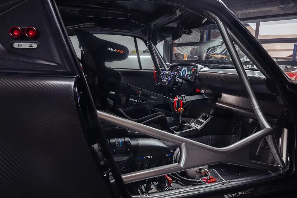 Intérieur d'une voiture de course avec arceau de sécurité et tableau de bord numérique.