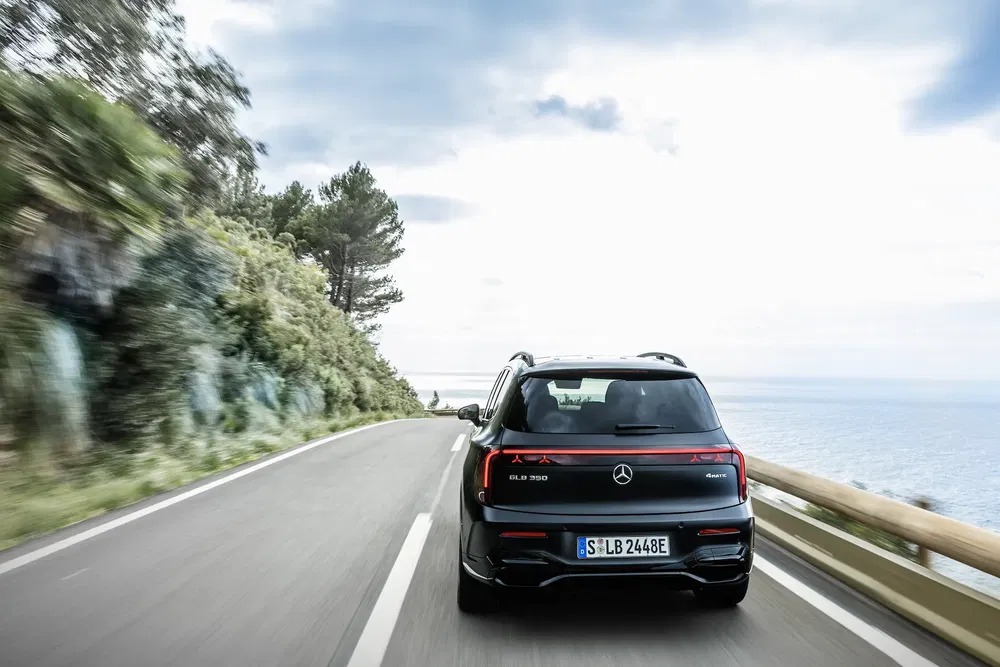 Mercedes-Benz EQB 350 longeant une route côtière bordée de verdure.