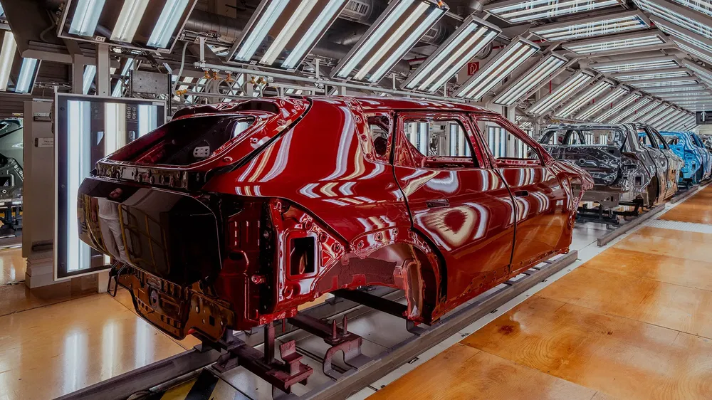Autoproductielijn met rood glanzend gespoten carrosserie onder felle verlichting.