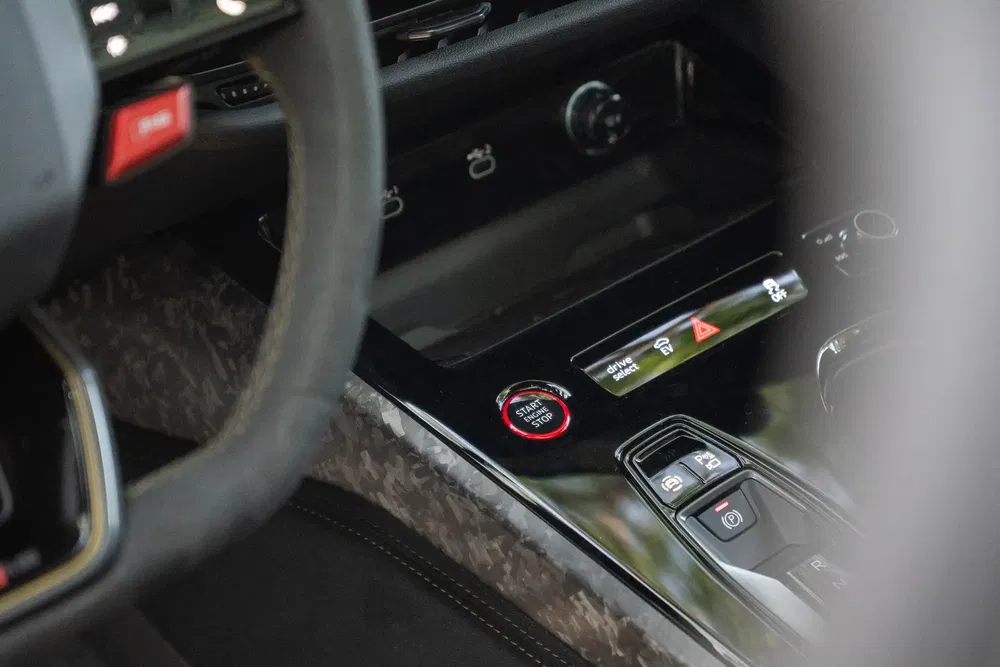 Startknop van Ferrari met koolstofvezel accenten en modern schakelpaneel.