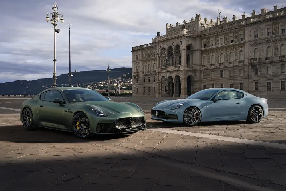 Deux modèles Maserati Granturismo parkés devant un bâtiment historique sur une place pavée.
