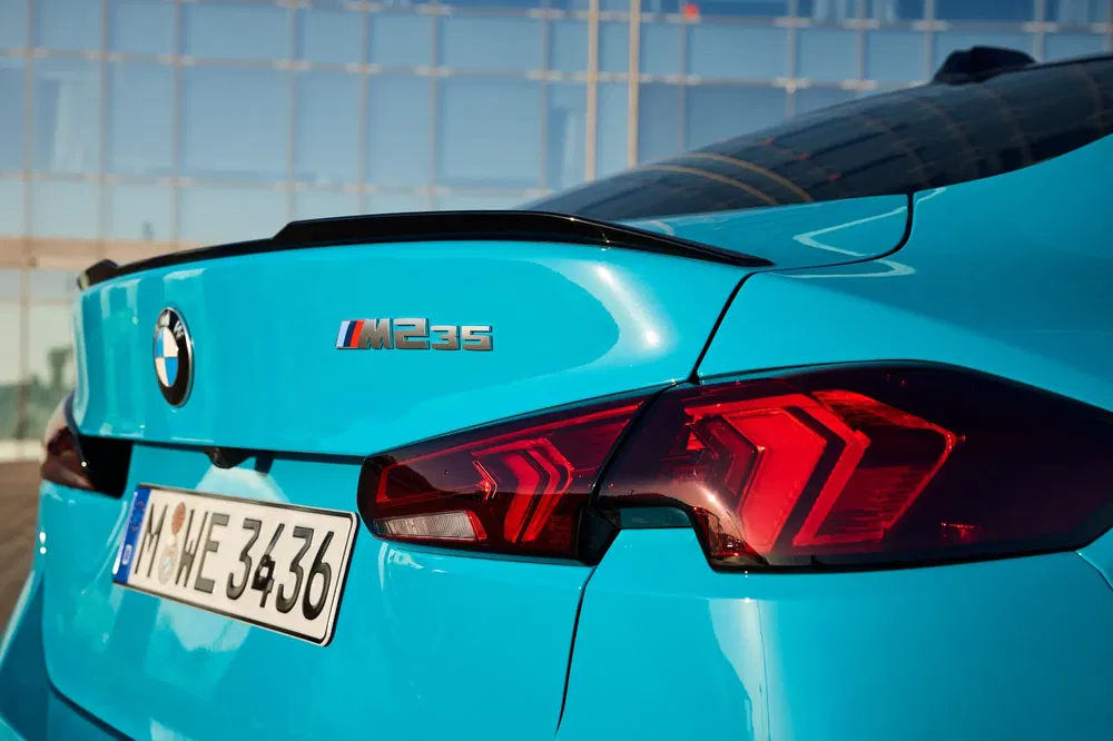 Vue arrière d'une BMW M235i bleue avec des feux arrière distinctifs et le logo M235.