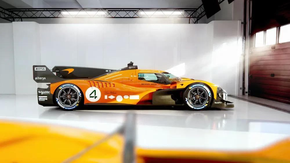 Voiture de course Hypercar orange vif, design aérodynamique dans un garage moderne éclairé.