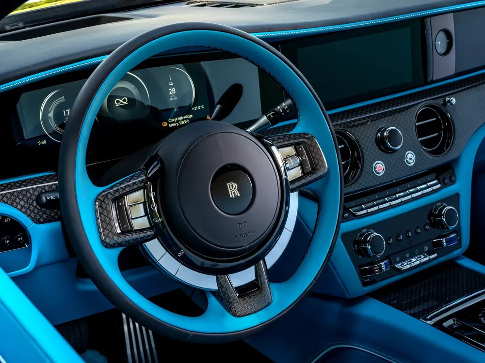 Intérieur luxueux d'une Rolls-Royce avec volant bleu et tableau de bord moderne.