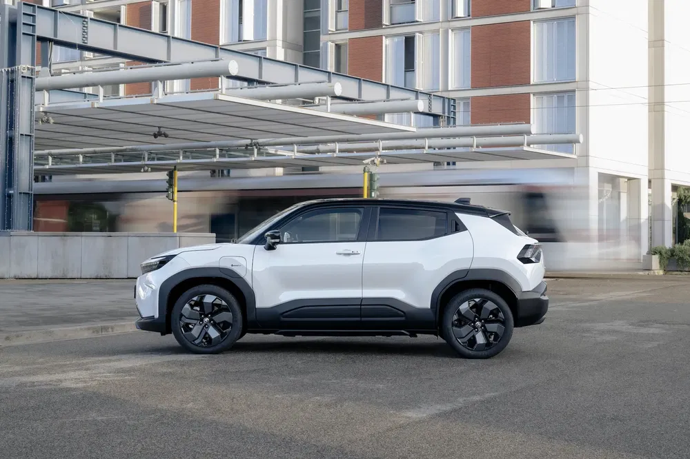SUV blanc garé devant bâtiment moderne, circulation floue en arrière-plan.