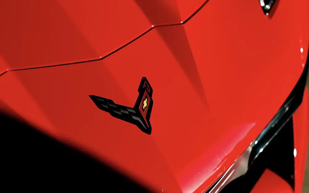 Chevrolet Corvette logo op felrode motorkap, sportief en modern design.
