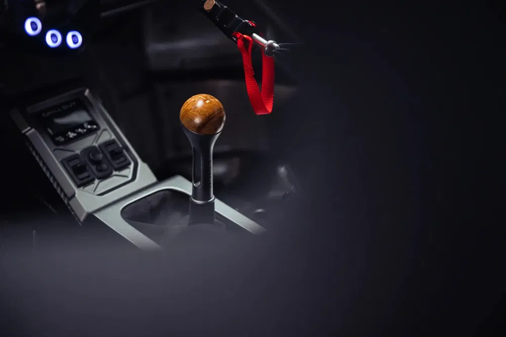 Levier de vitesse en bois dans une voiture de sport avec intérieur sombre et moderne.