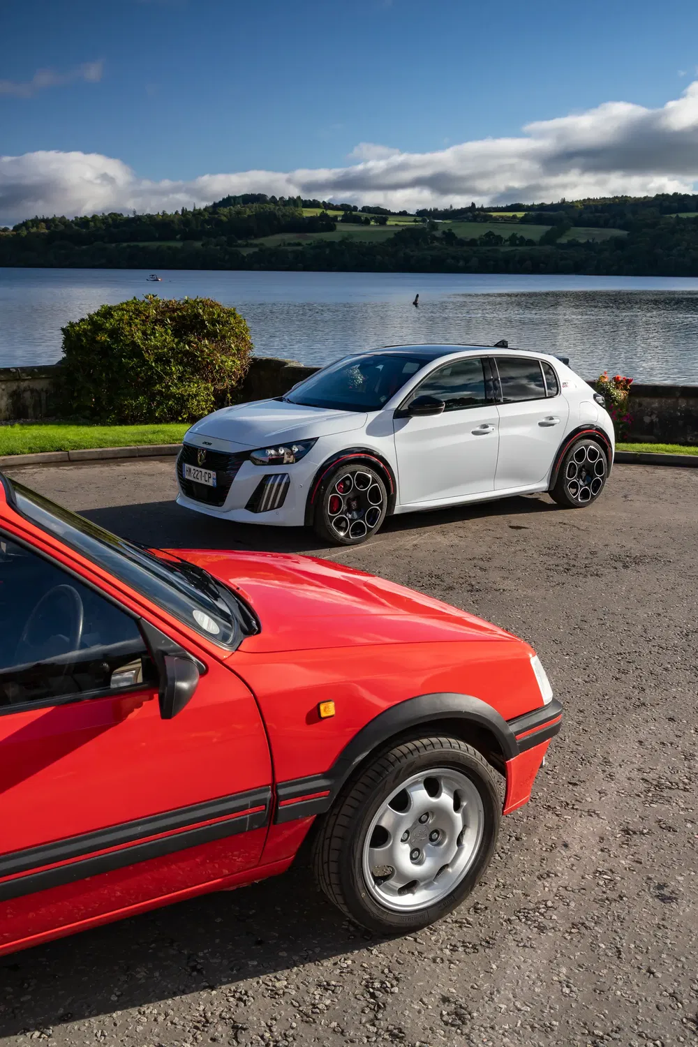 Peugeot 208 moderne et modèle classique au bord d'un lac pittoresque.