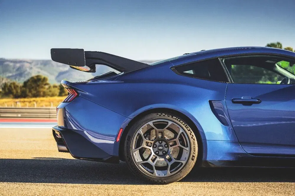 Aileron arrière de Chevrolet Camaro bleu sur circuit, design sportif et dynamique.