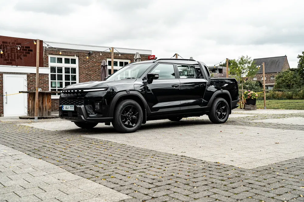 Zwarte Haval pickup geparkeerd op een geplaveid plein voor een bakstenen gebouw.
