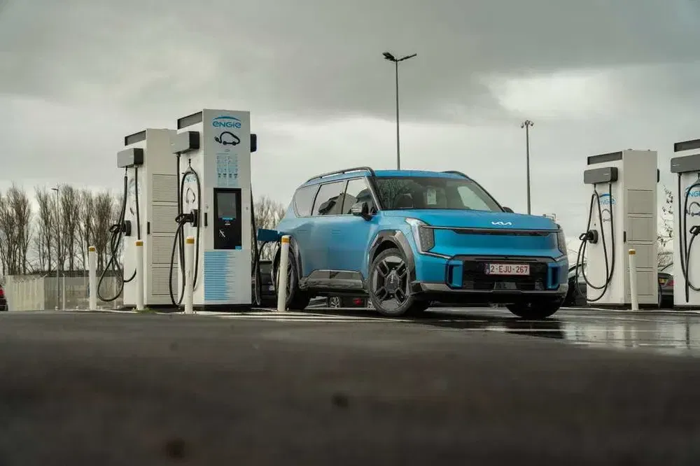 Blauwe elektrische Kia bij een Engie-laadstation onder een bewolkte hemel.