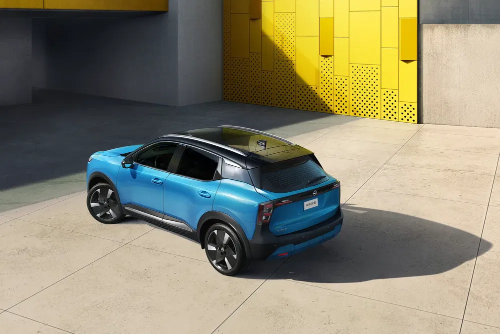 Blauwe Nissan Qashqai geparkeerd voor een moderne, gele geometrische muur.