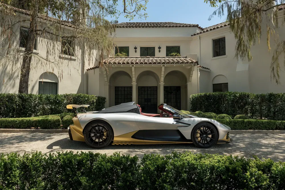 Voiture de sport Pininfarina Battista, argent et or, devant une villa élégante.