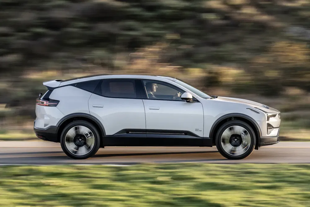 Voiture électrique Polestar 3 blanche roulant sur une route, design moderne et futuriste.
