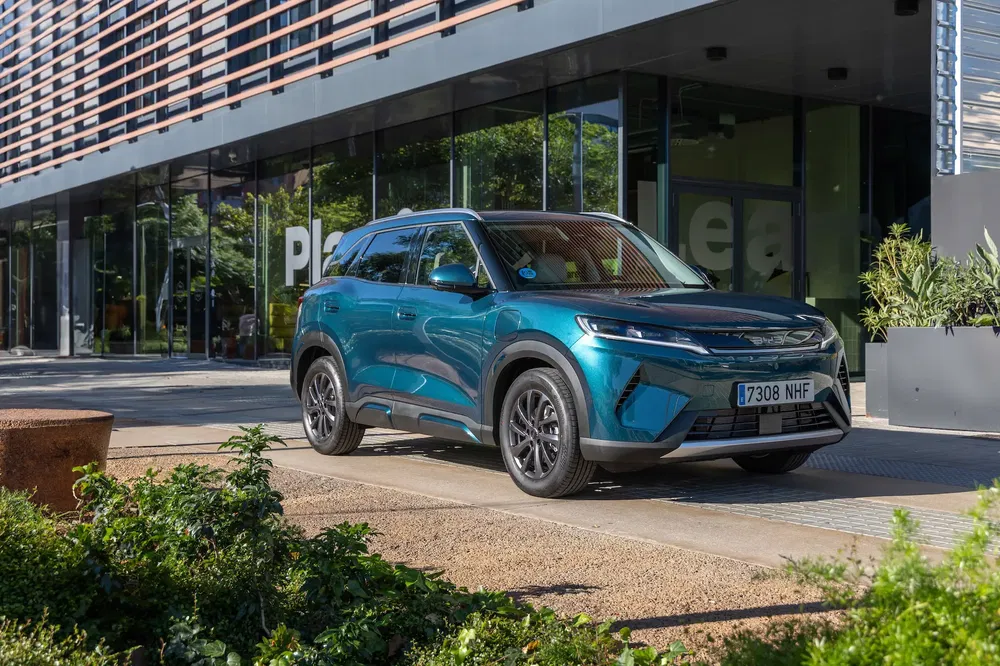 SUV blue moderne garé devant un bâtiment commercial avec des plantes.