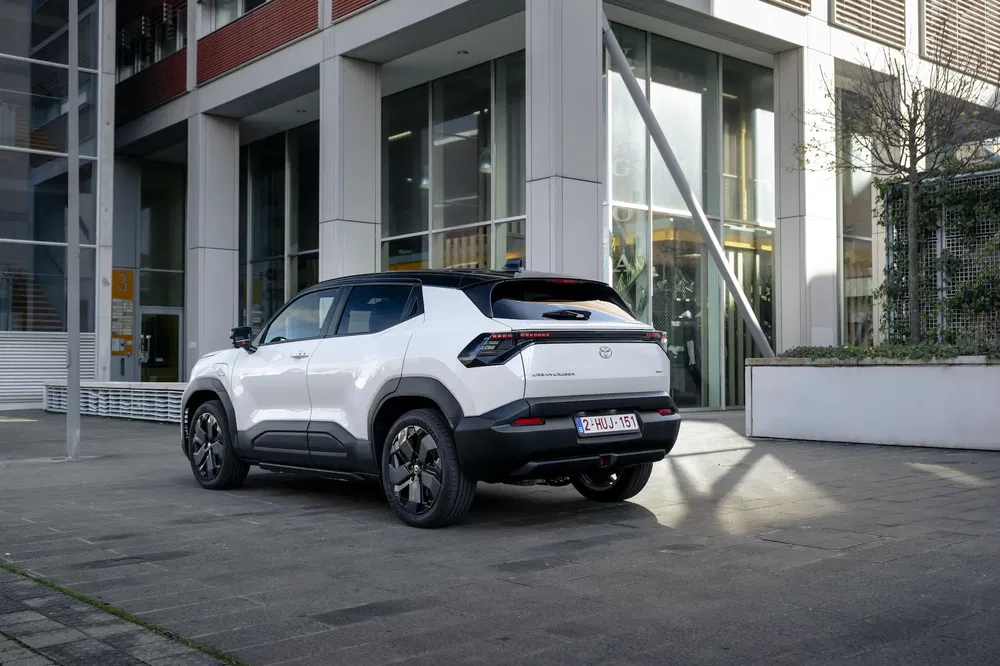 Toyota Yaris Cross blanche stationnée devant un bâtiment moderne urbain.