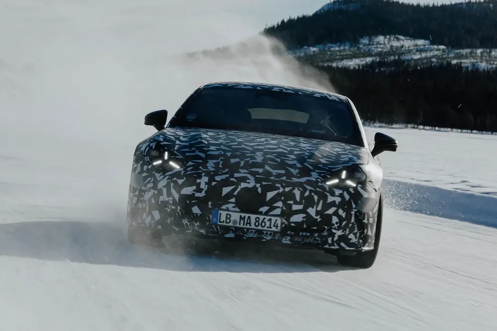 Voiture camouflée effectuant un test de conduite sur une route enneigée en hiver.