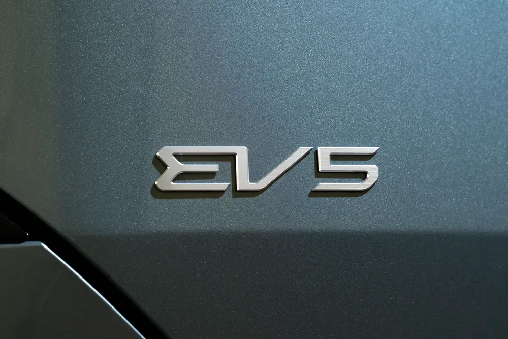 Close-up van het EV5-logo op de grijze carrosserie van een elektrische auto.