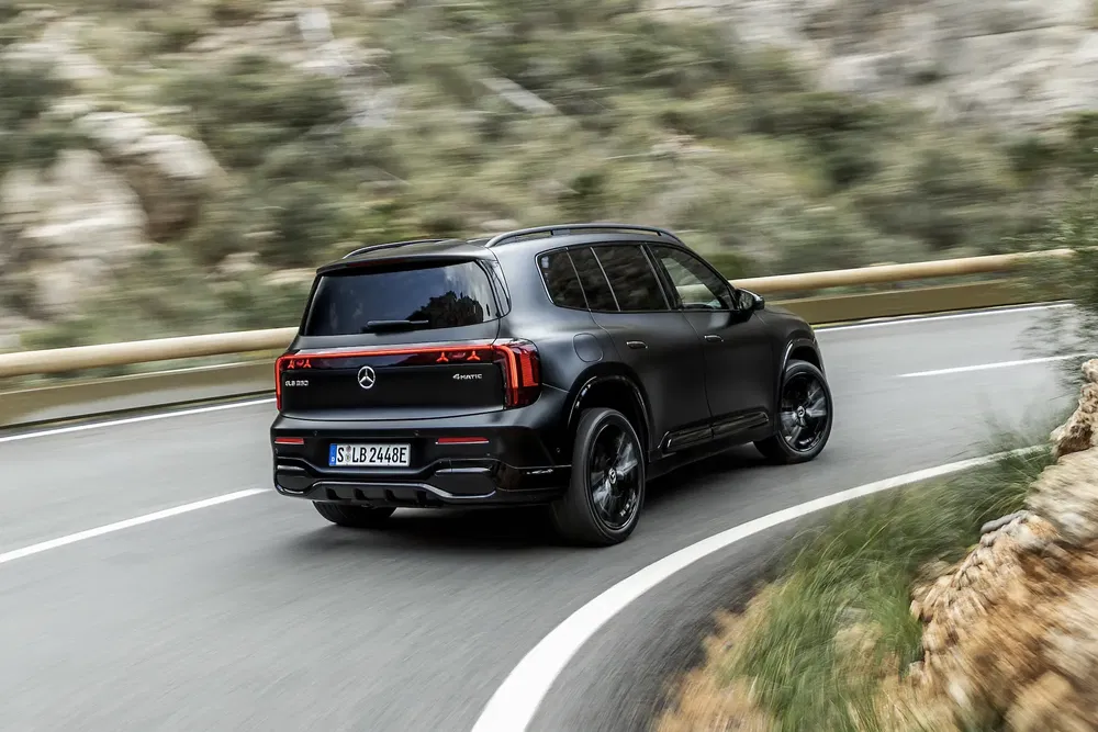 Mercedes-Benz EQB noir roulant sur route sinueuse en montagne.