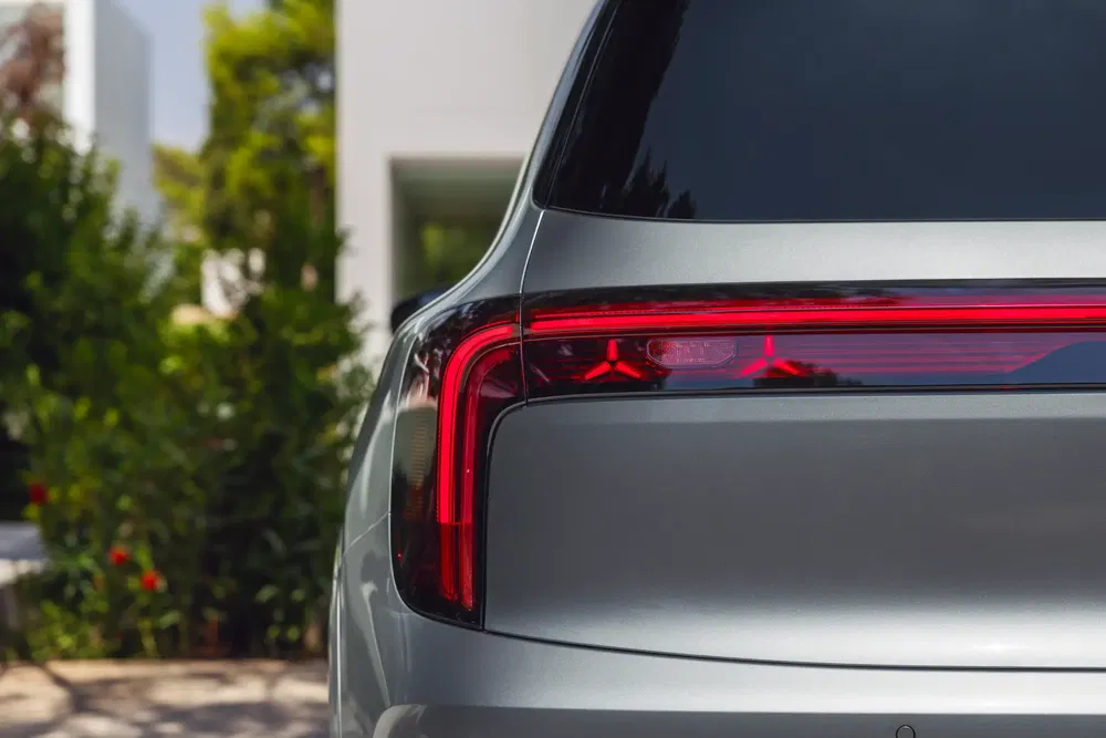 Feux arrière LED d'une voiture électrique argentée moderne, accentués par un cadre verdoyant.
