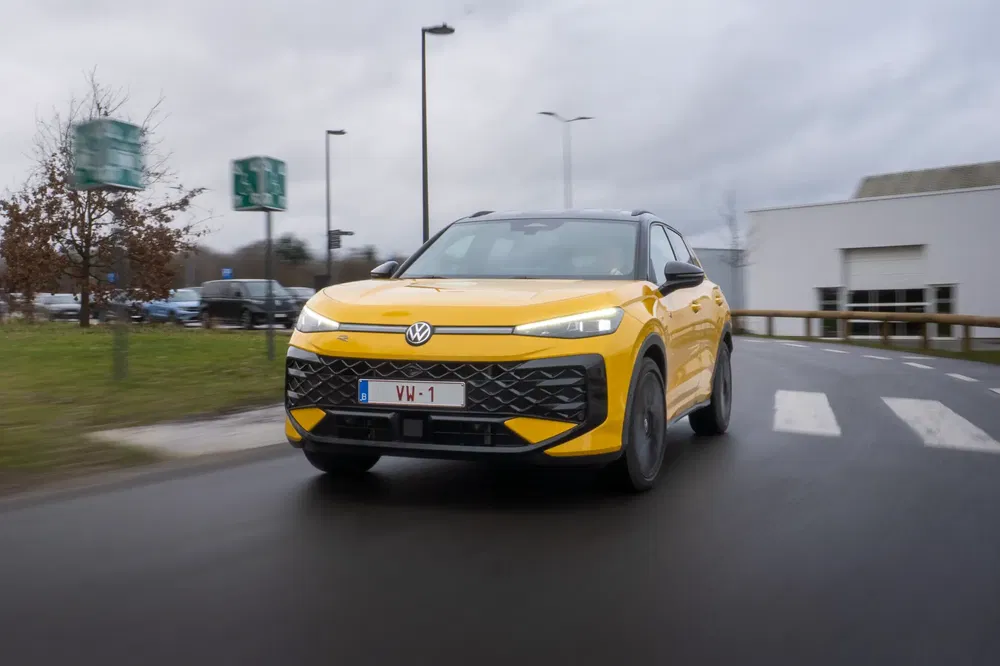 Volkswagen ID.4 jaune brillant sur route urbaine par temps nuageux.