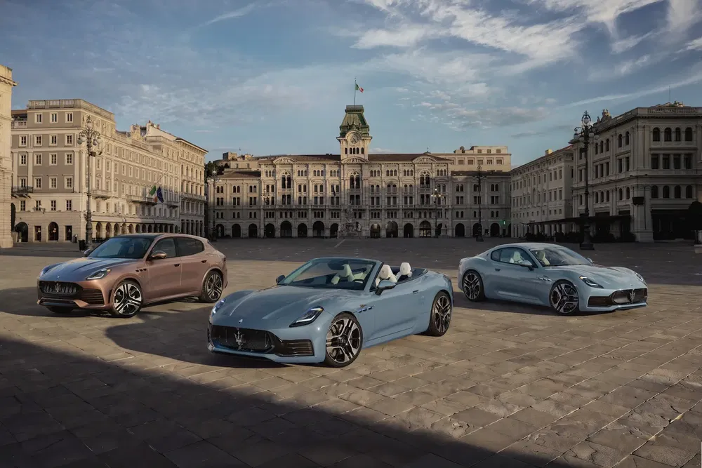 Trois voitures Maserati modernes sur une place italienne historique, architecture classique en arrière-plan.