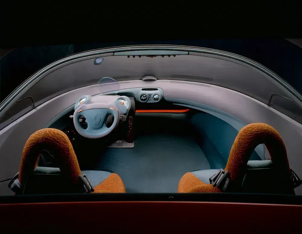 Interieur van Renault conceptauto met futuristisch stuur en opvallende oranje stoelen.