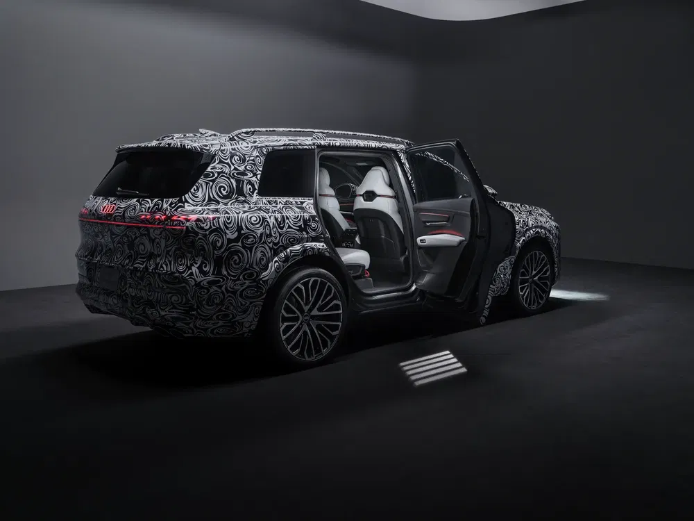 SUV Audi en camouflage, portes ouvertes révélant l'intérieur moderne et spacieux.