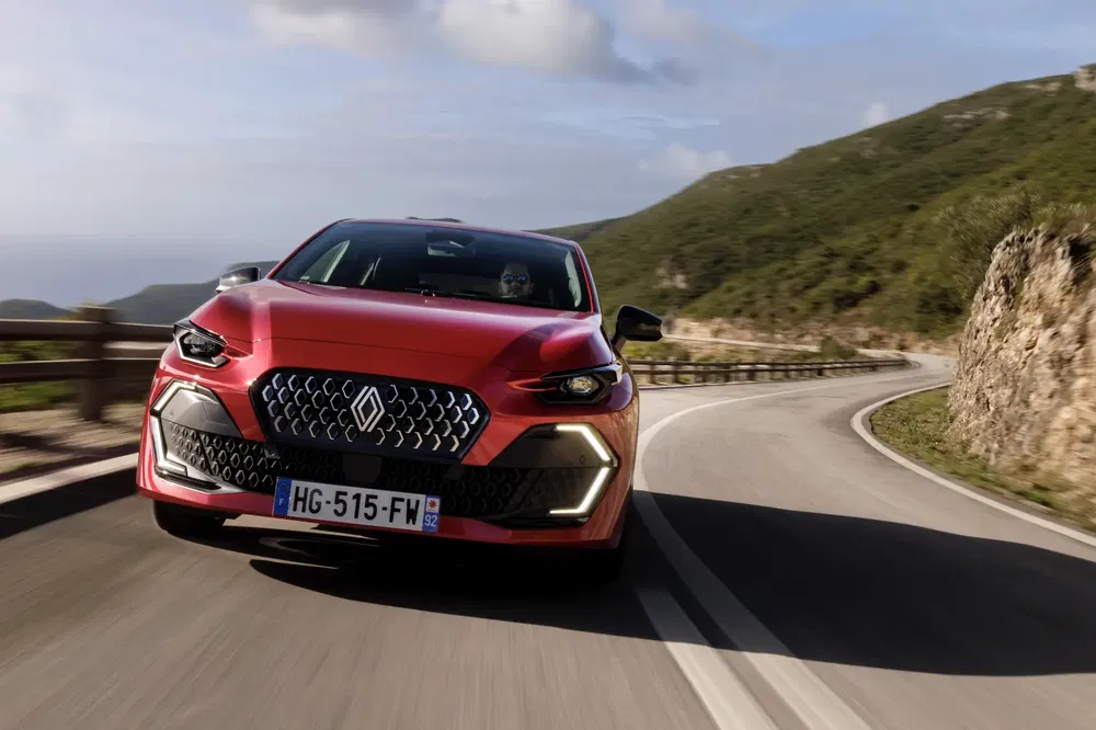 Voiture rouge moderne sur route sinueuse avec plaque d'immatriculation française.