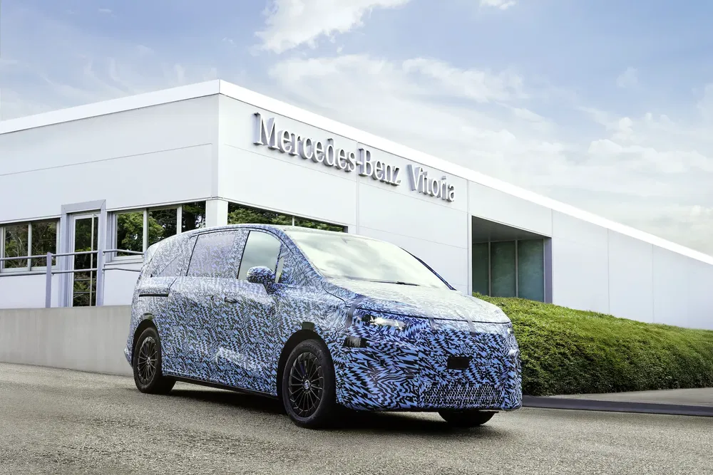 Prototype fourgon Mercedes-Benz camouflé devant l'usine Vitoria, ciel dégagé.