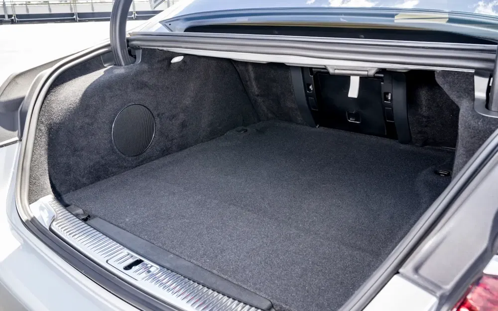 Coffre spacieux et bien aménagé d'une Mercedes-Benz Classe E, avec tapis gris foncé.