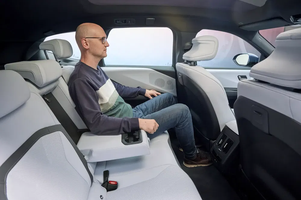 Man zit achterin een BMW iX, modern en ruim interieur.