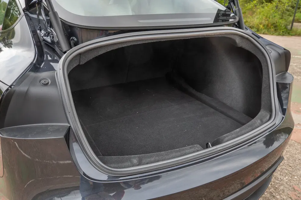 Coffre spacieux d'une Tesla Model 3 ouvert sur fond extérieur.