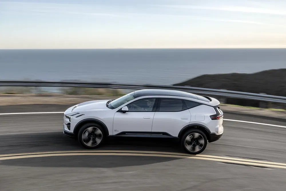 Polestar 3 électrique roulant sur une route côtière, vue latérale dynamique.